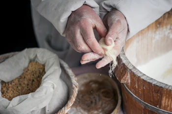 Hands crafting traditional corn-based food in a rustic kitchen setting.