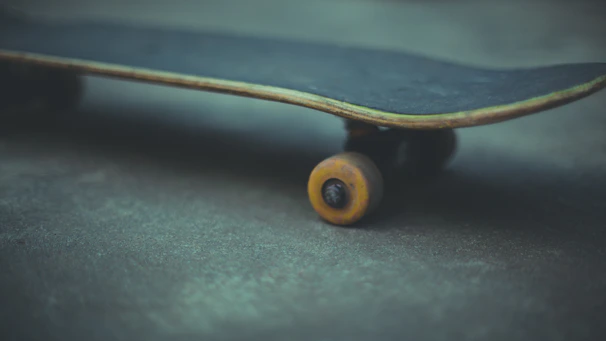 Skateboard resting on asphalt with Kronos Bearings logo sharply in focus.