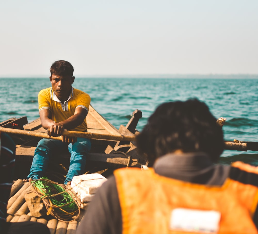 man padding inside boat on sea during daytime