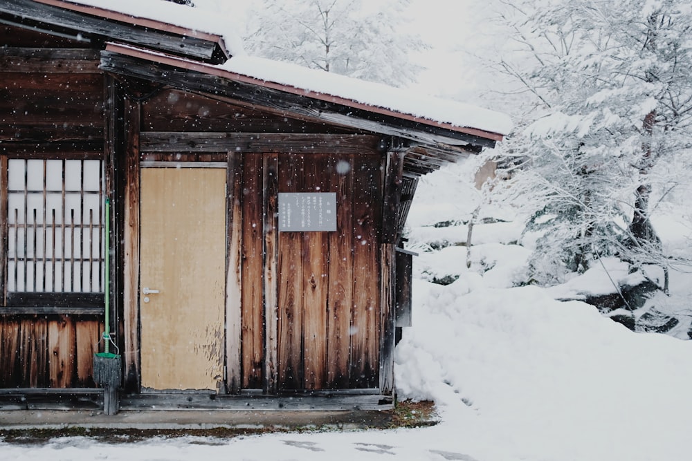 Braunes Holzhaus, das tagsüber mit Schnee bedeckt ist