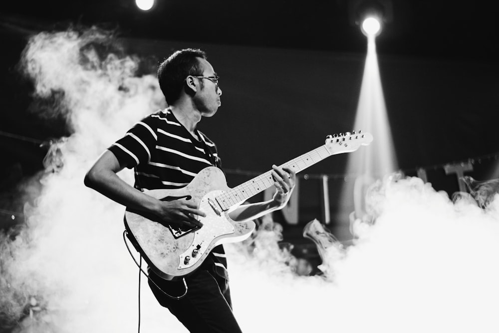 man playing guitar on stage with smoke