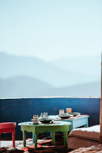 Sunlit table in mountain lodge setting with earthy ceramic bowls of fresh traditional dishes surrounded by desert plants.
