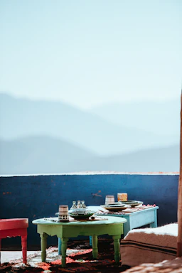 Sunlit table in mountain lodge setting with earthy ceramic bowls of fresh traditional dishes surrounded by desert plants.