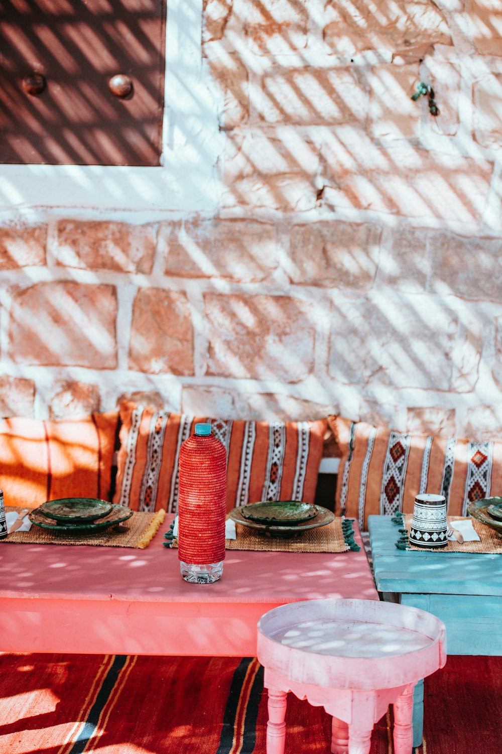 red plastic bottle on top of table near to wall