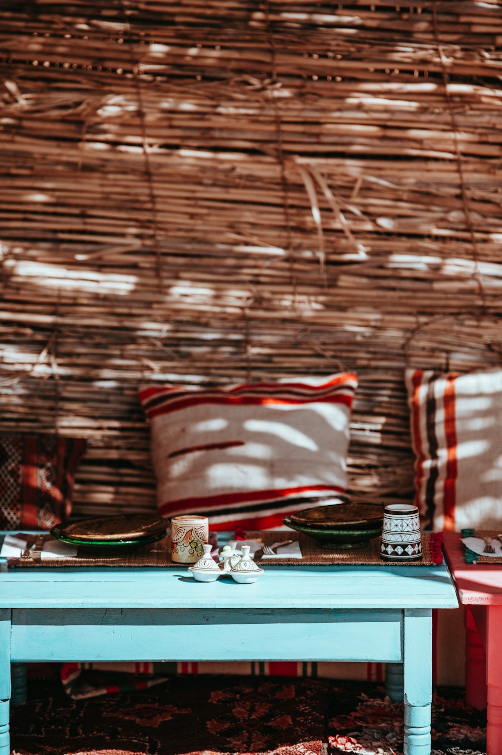 Deux coussins carrés blancs-rouge-noir sur une table en bois bleu