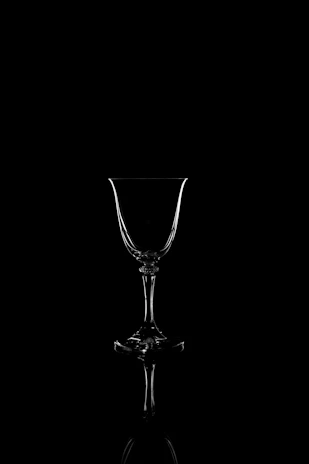Close-up of a crystal wine glass catching muted gold light, set against a charcoal backdrop.