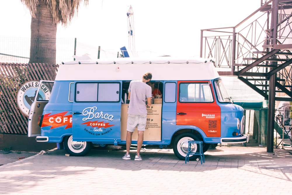 man standing near blue van during daytime photo