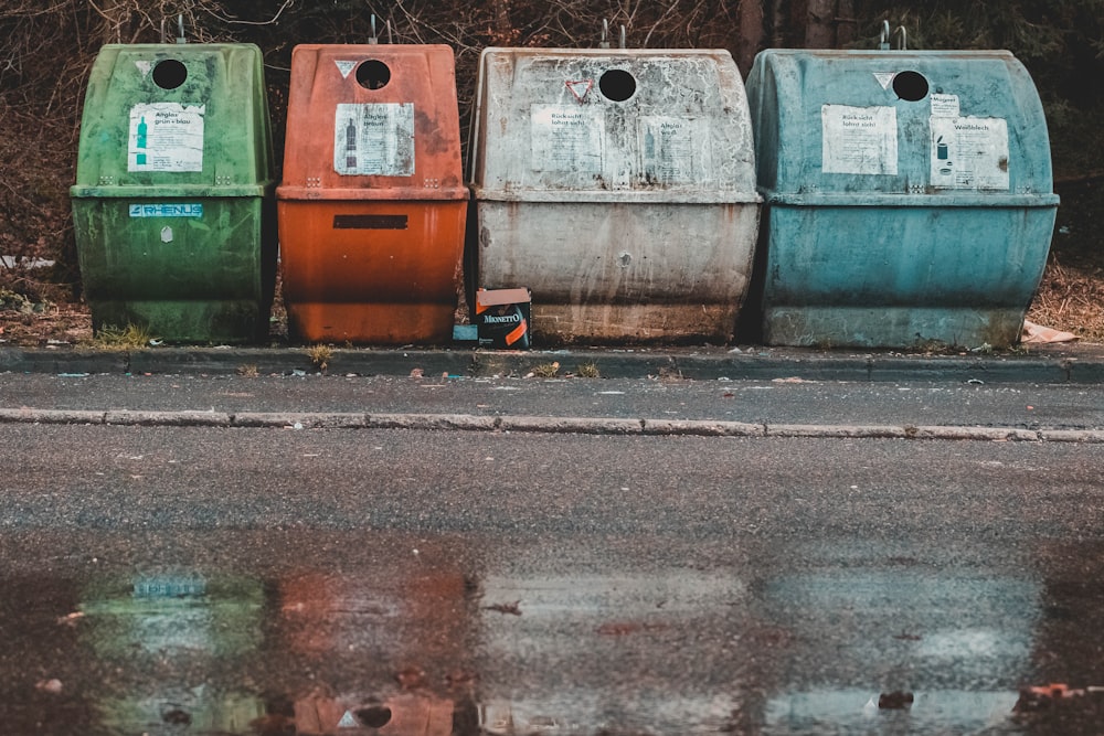 Foto de quatro poços de compostagem de cores variadas perto de estrada vazia