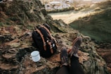 person wearing pair of brown boots sitting in front of black backpack