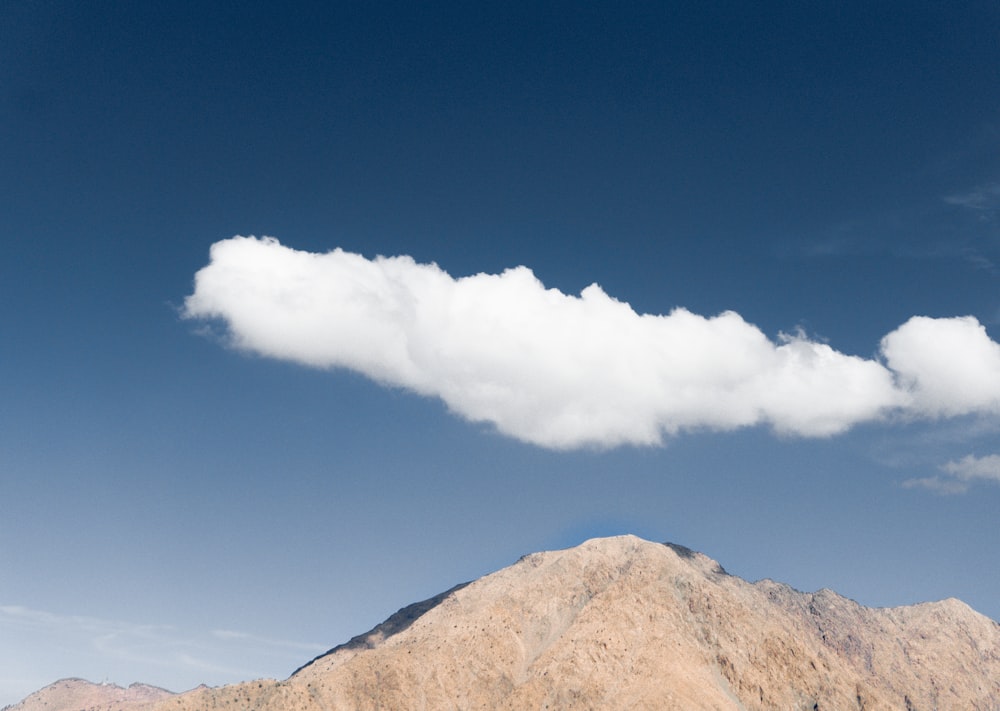 brown mountain under white clouds and blue sky during daytime