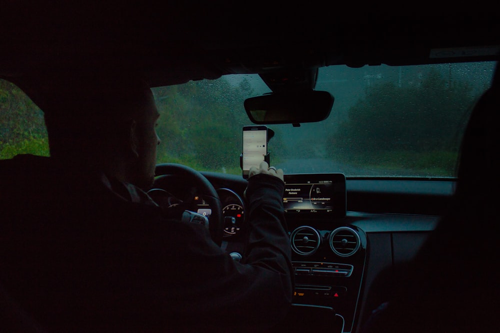 Person, die ein Auto mit einem Telefon fährt