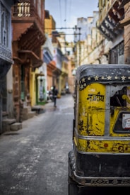 selective focus photography of yellow auto rickshaw on road