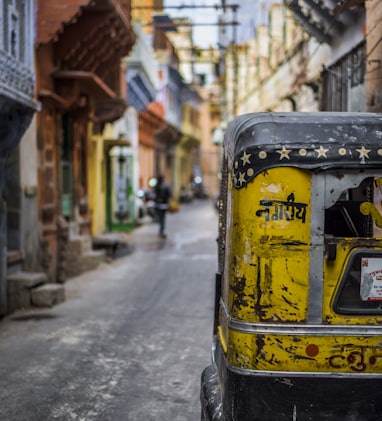 selective focus photography of yellow auto rickshaw on road