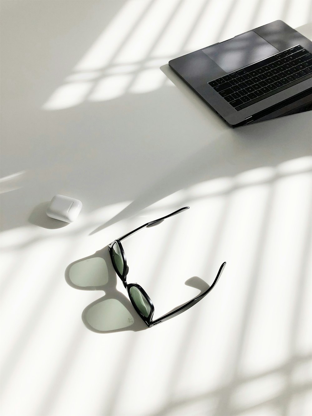 flat-lay photography of wayfarer-style sunglasses and MacBook Pro