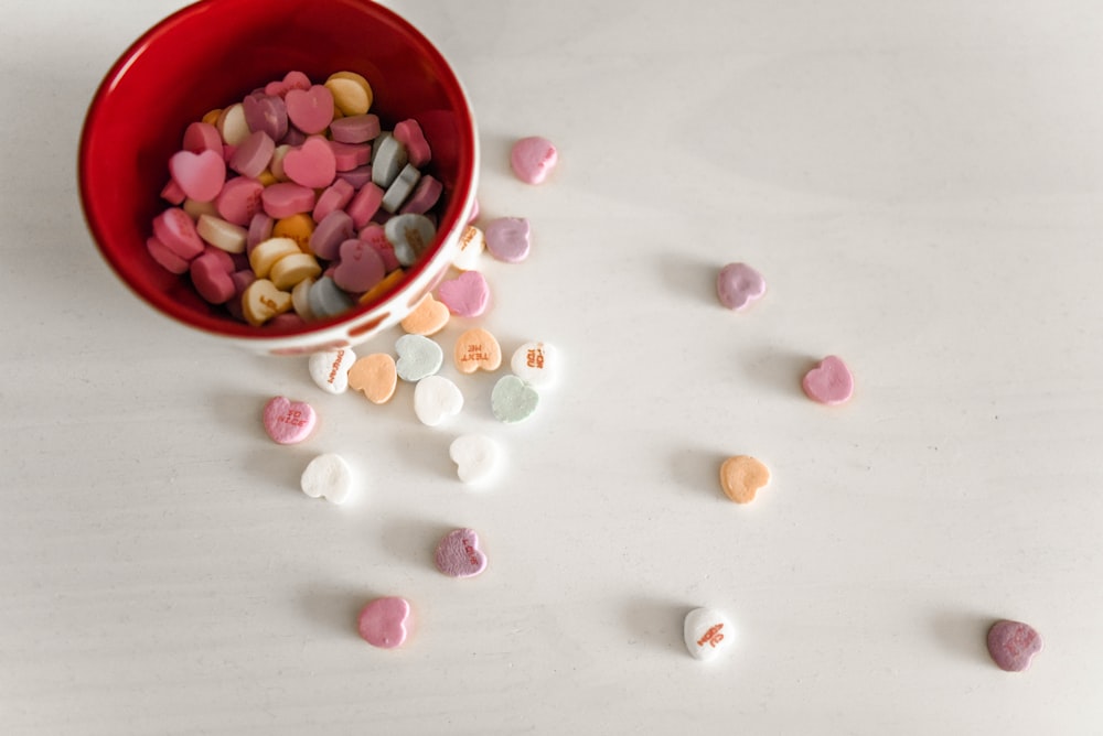 bonbons de couleurs assorties et bol en céramique rouge et blanc