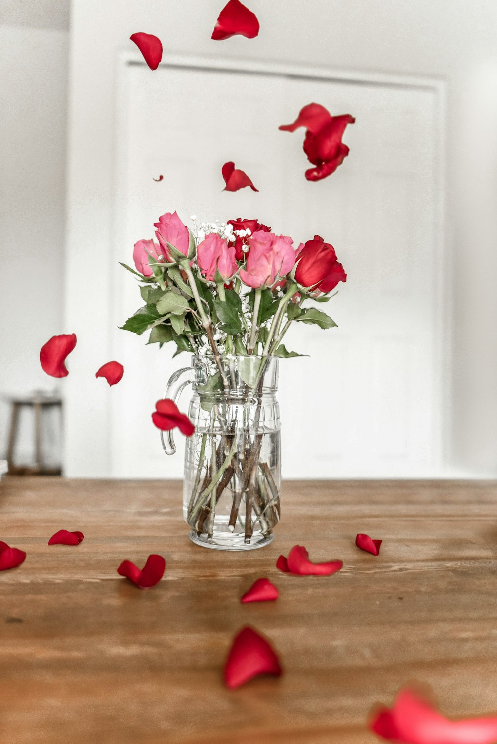 透明なガラスの花瓶にピンクと赤のバラ