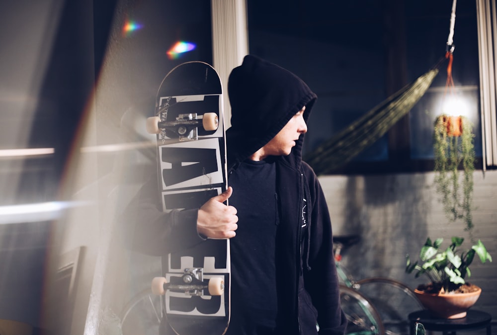 man in hoodie holding skateboard