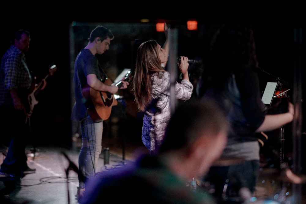 woman holding microphone singing beside man playing guitar