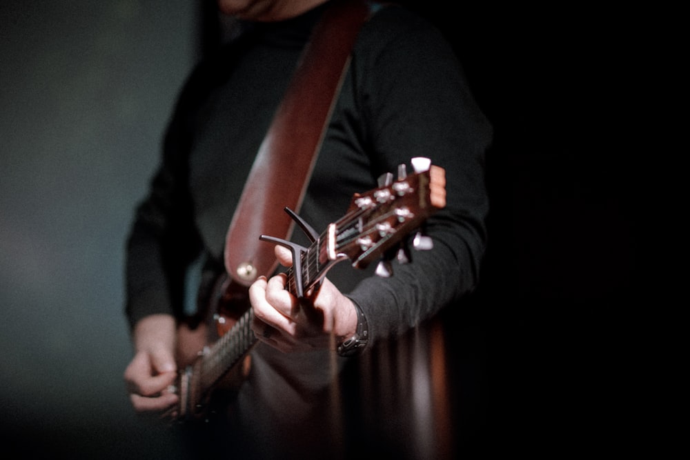 Persona que toca la guitarra marrón