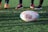 Close-up of rugby boots and a ball on green grass.