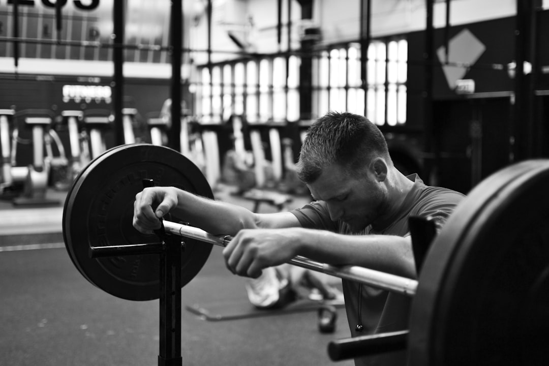 gray scale photo of man sitting on bench press