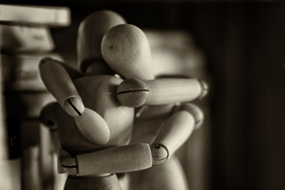 dois bonecos de madeira abraçando figuras