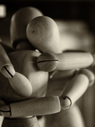 two wooden dummy hugging figures