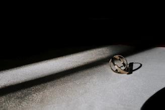 High-end 3D render of intertwined golden rings casting dynamic shadows on a sleek black surface with subtle glowing accents.