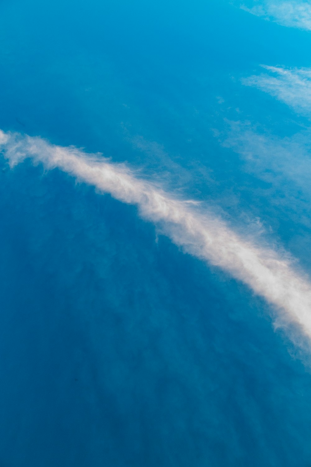 a jetliner flying through a blue cloudy sky