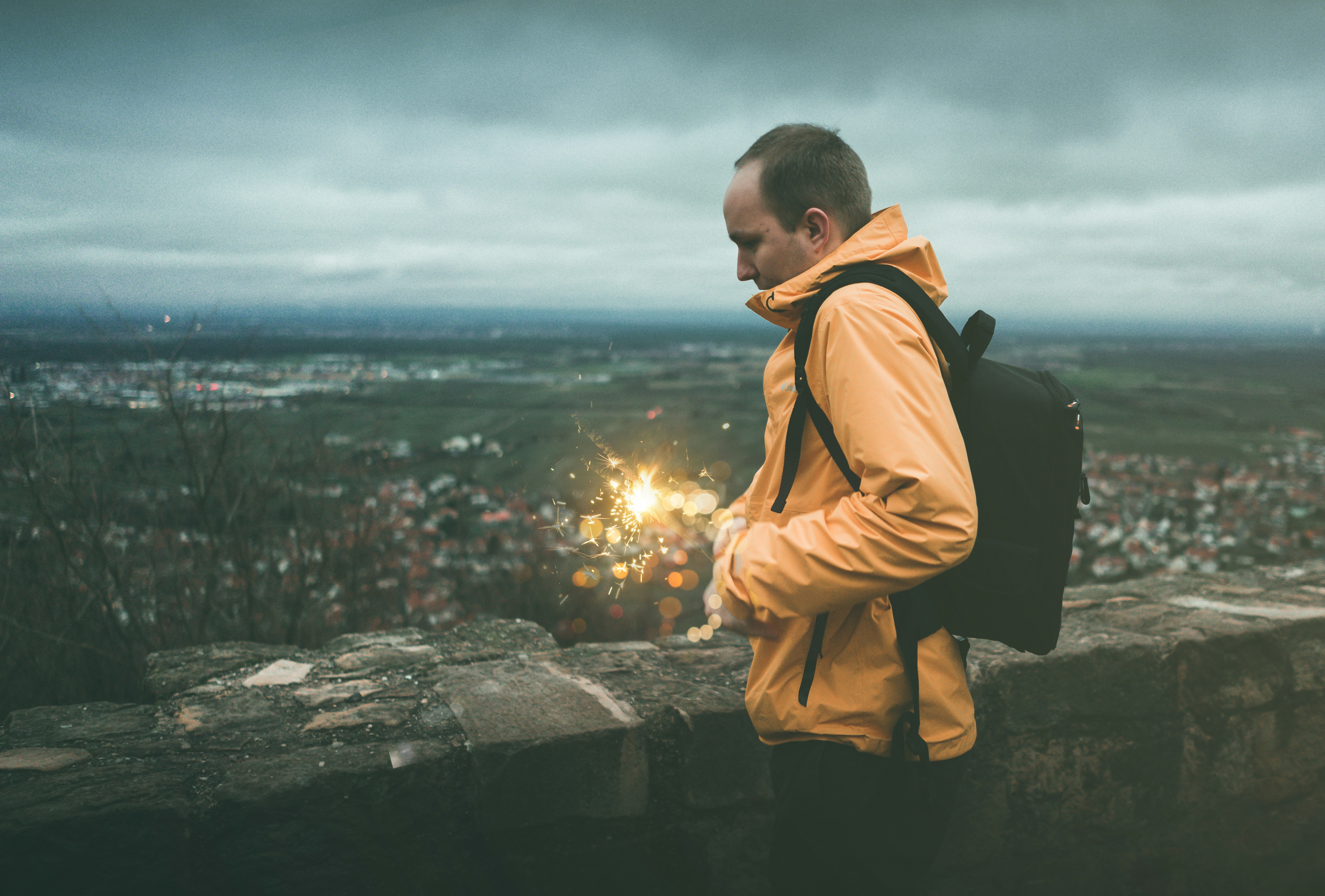 woman wearing orange jacket and black backpack wanderer teams background