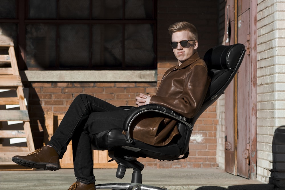 homme assis sur un fauteuil roulant de bureau en cuir noir