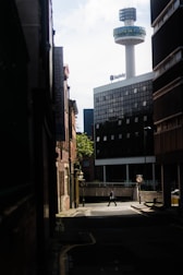 A detective tailing a subject on foot through a quiet city street.