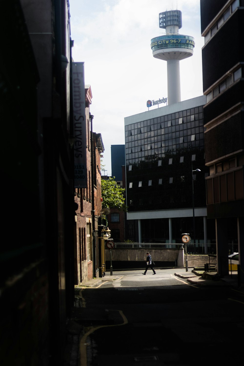 a man walking down a street next to tall buildings