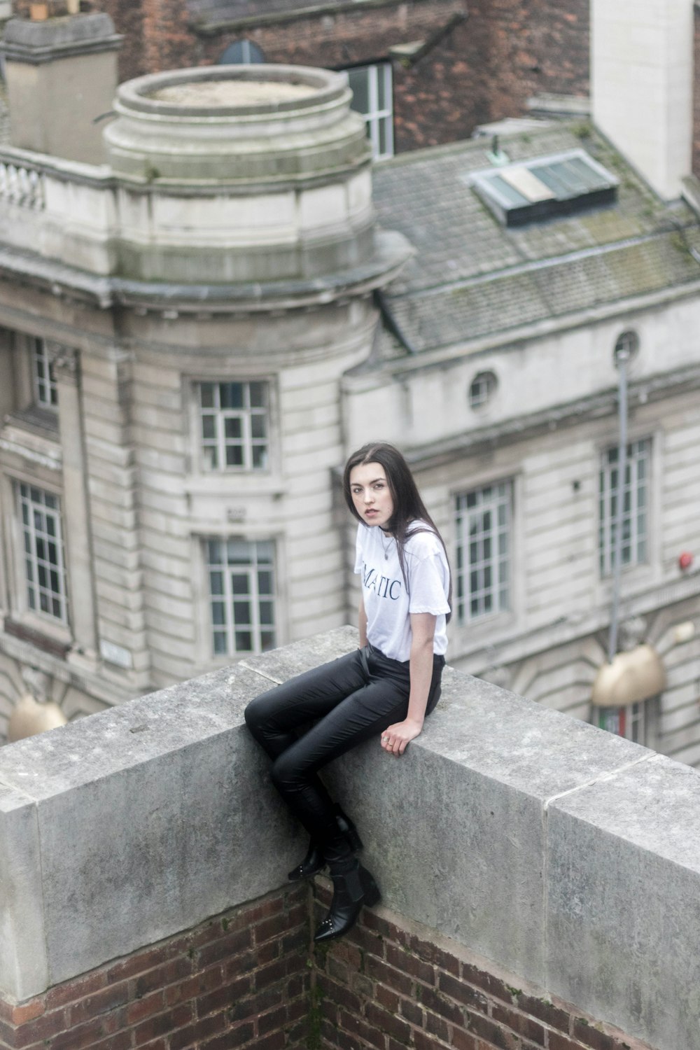 woman in white shirt sitting on top of building
