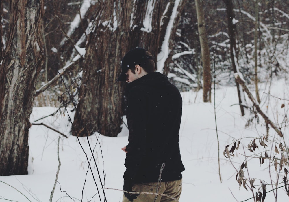 man wearing jack standing between trees with snow