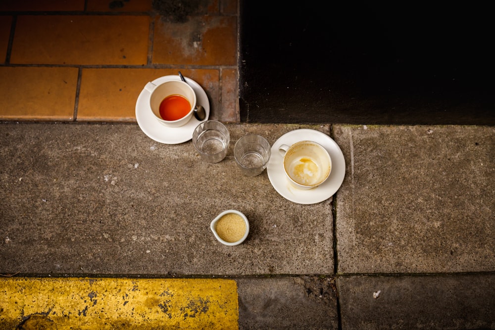 three beverage filled mugs and two empty drinking glasses