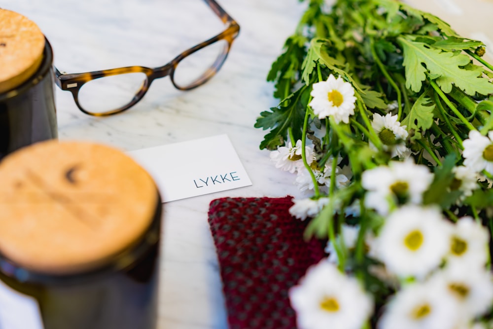 shallow focus photo of eyeglasses beside flower