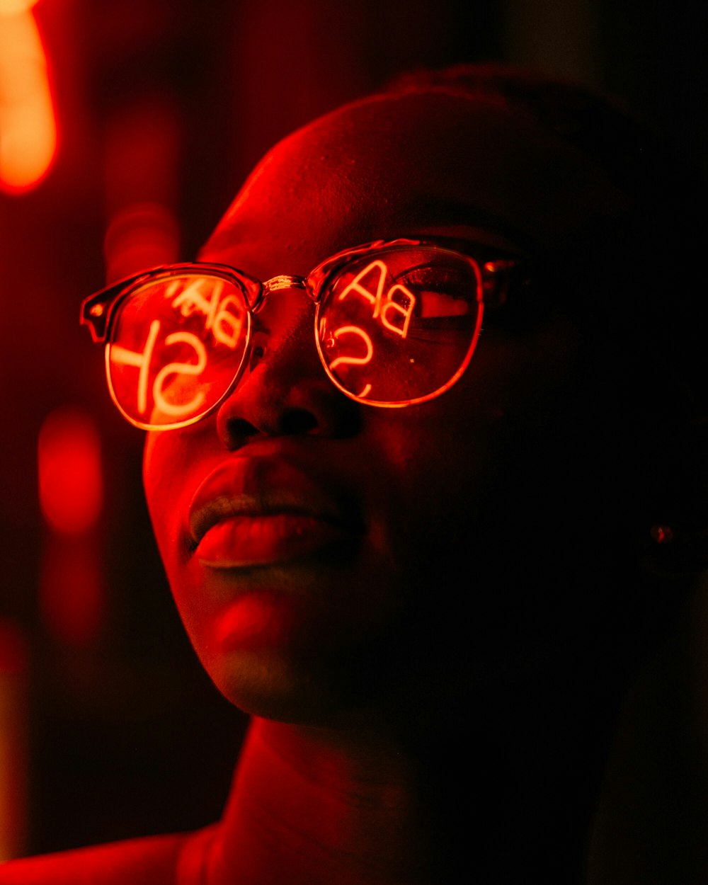 woman wearing eyeglasses with red LED signage reflection