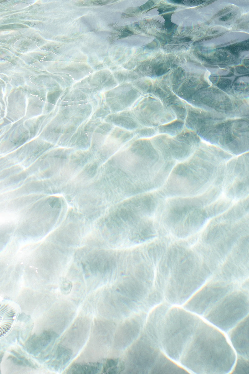 Sunlit pool water sparkling in soft pastel light, calm and clean.