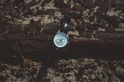 Close-up of a pilot's watch with a worn leather strap resting on a vintage flight logbook.