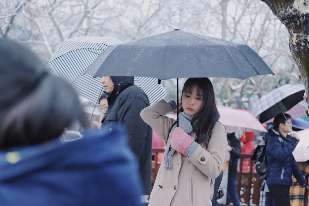 femme en manteau beige tenant un parapluie