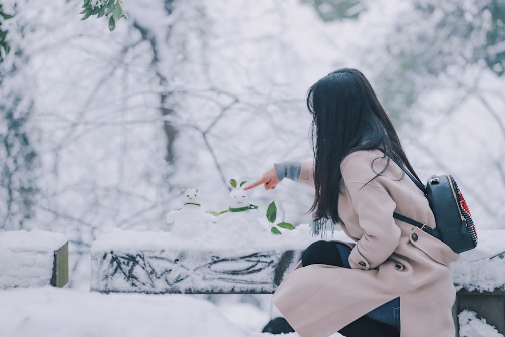 woman wearing brown coat touching snow