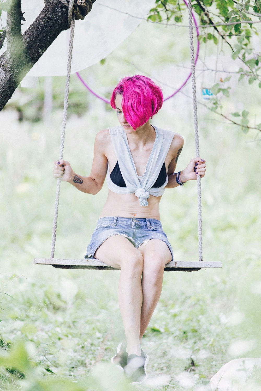 woman sitting on swing under tree during daytime