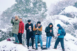 A diverse group of people dressed warmly, reading snow safety tips on a digital tablet in a snowy Australian landscape.
