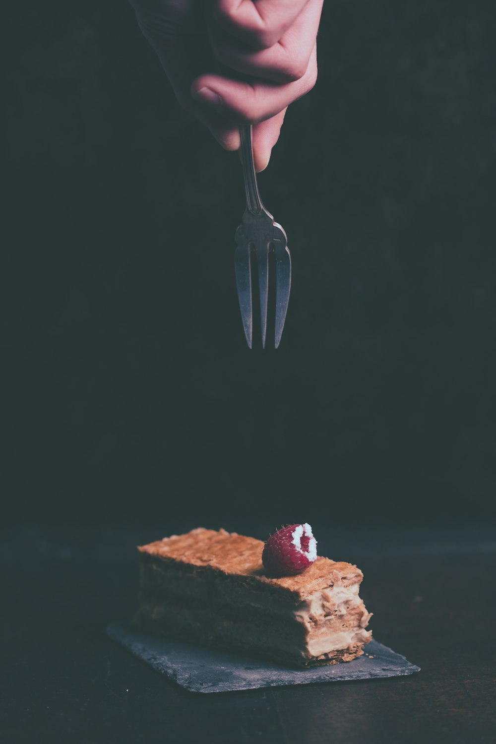 persona sosteniendo un tenedor a punto de agarrar el pastel