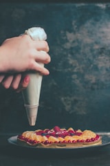Close-up of a chef carefully decorating a delicate pastry with fresh fruit.