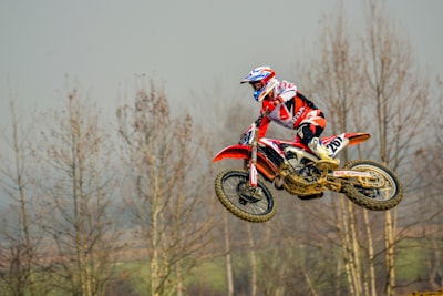 man playing dirt bike at daytime honda teams background