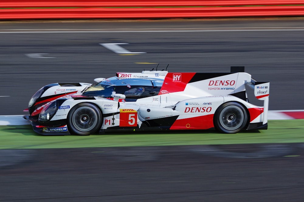 white and red denso supercar on racing field