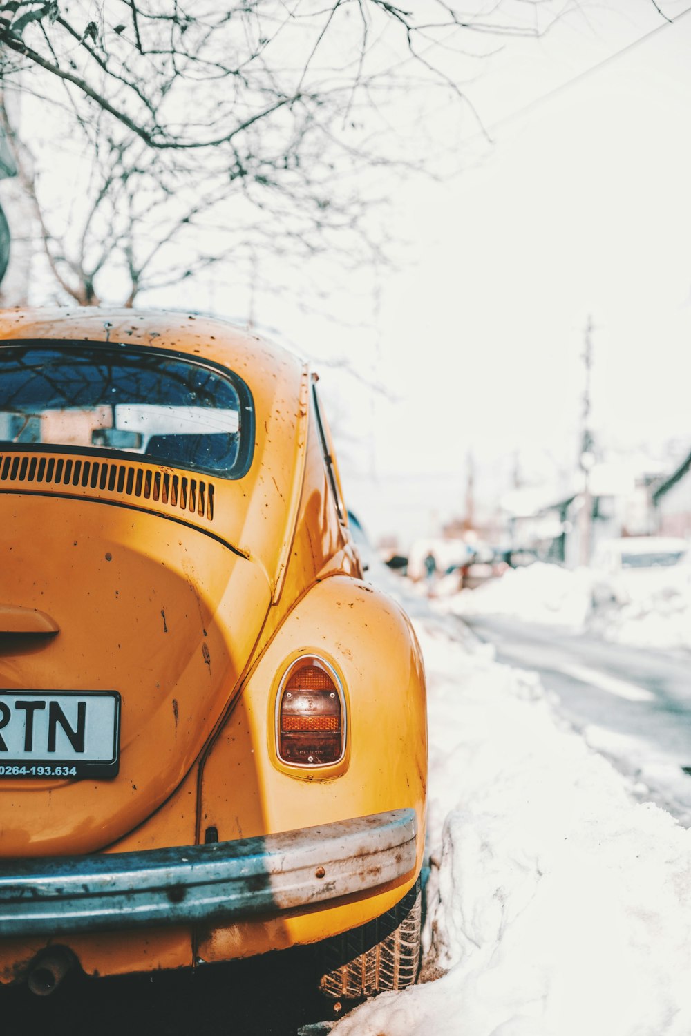 yellow Volkswagen Beetle parked near road