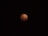 A celestial event captures the Earth's shadow covering the moon, giving it a reddish hue known as a blood moon, set against a black night sky.